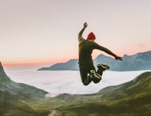 Ein Mann springt in die Luft und vor ihm ist eine Berglandschaft