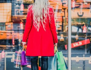Eine Frau in roten Mantel steht vor einem Geschäft mit vielen Sale-Angeboten