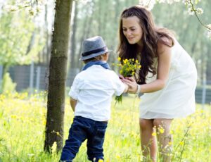 Ein Kind schenkt einer Frau auf einer Wiese selbst gepflückte Blumen