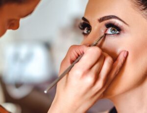 Makeup-Artist trägt Lidschatten bei einer jungen Frau auf
