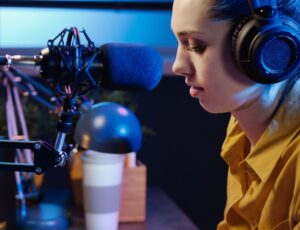 Junge Frau spricht in Mikrofon und sitzt in einem Büro vom Radio