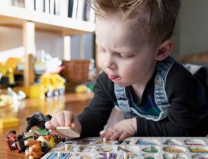 Kleiner Junge spielt auf dem Boden zuhause mit einem ABC-Puzzle