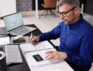 Mann kalkuliert mit Taschenrechner im Büro