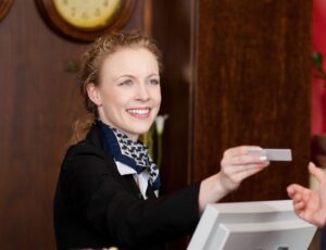 Rezeption in einem Hotel: Hotelmitarbeiterin übergibt Schlüsselkarte an eine junge Frau