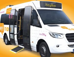 Ein weißer Kleinbus mit der Aufschrift „Hey! Move“ und dem Namen „Heyko“ vor einem orangefarbenen Hintergrund. Die Tür des Busses ist geöffnet, und eine Rampe ist ausgeklappt, was Barrierefreiheit betont. Der Bus steht für die Digitalisierung des Nahverkehrs in Tuttlingen.