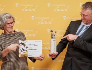 Zwei Preisträger der Oper Halle präsentieren Urkunde und Trophäe beim Staatsanzeiger Award 2025