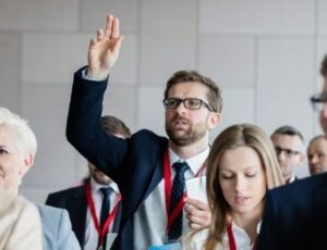 Geschäftsmann meldet sich in einem Seminar und stellt eine Frage